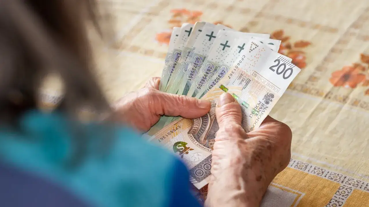 Dłonie starszej osoby liczą banknoty 200 zł. To może być przykład, co to jest okresowa emerytura kapitałowa.