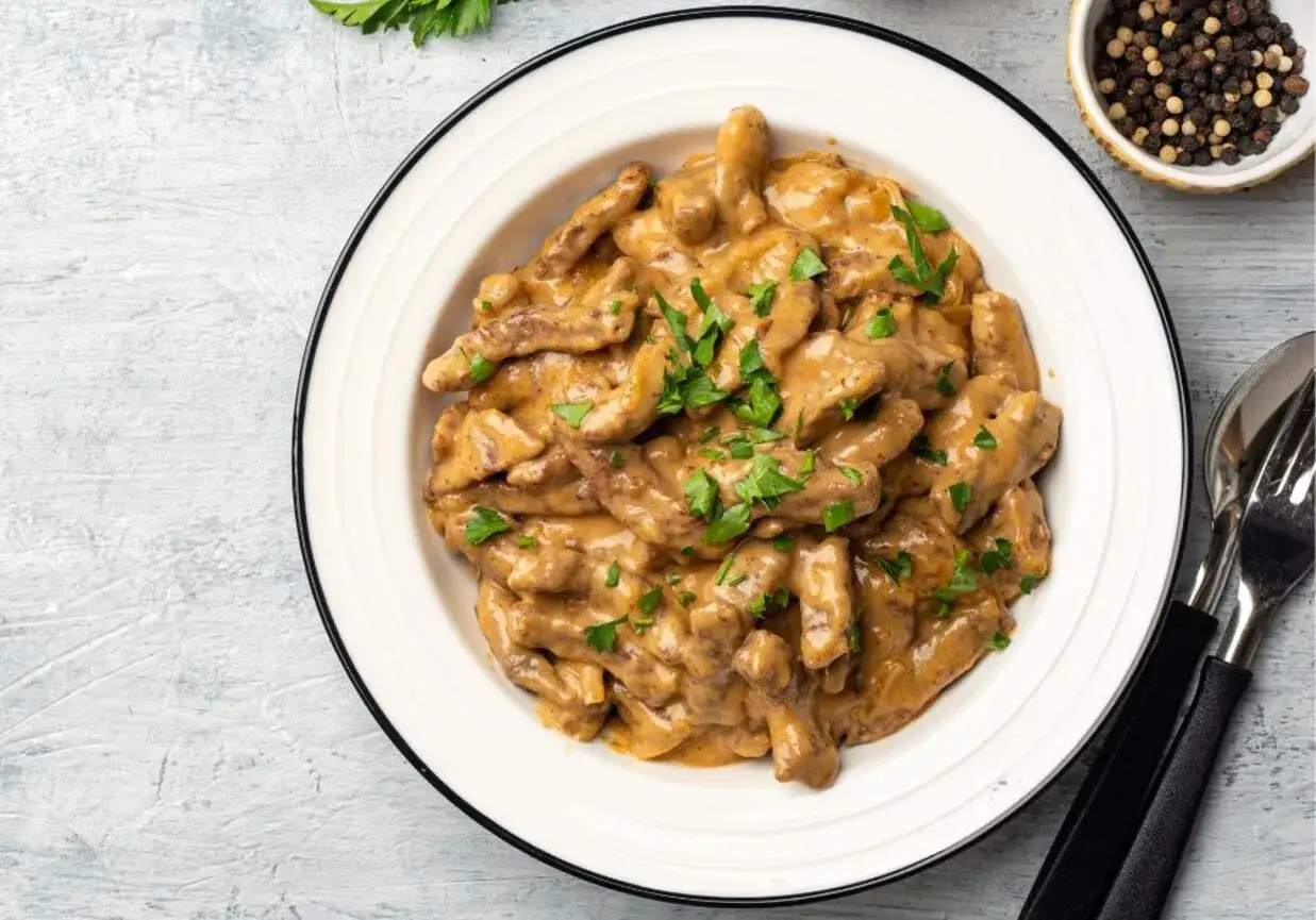 Pyszny gulasz z kruchym mięsem, przygotowany domowymi sposobami bez sztucznych zmiękczaczy. Posypany świeżą natką pietruszki.