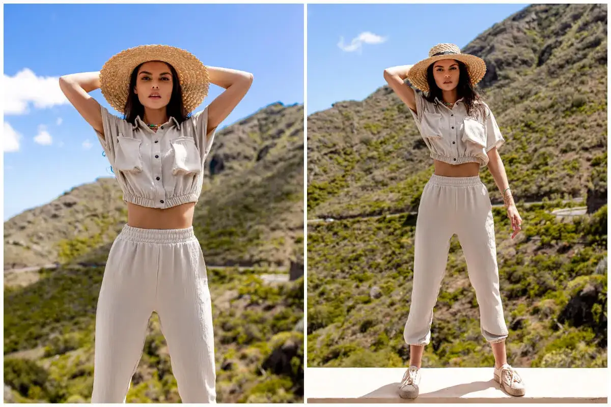 Modelka w beżowym komplecie z szerokimi spodniami i słomkowym kapeluszem pozuje na tle gór. Jaka góra do szerokich spodni – ten zestaw to strzał w dziesiątkę!