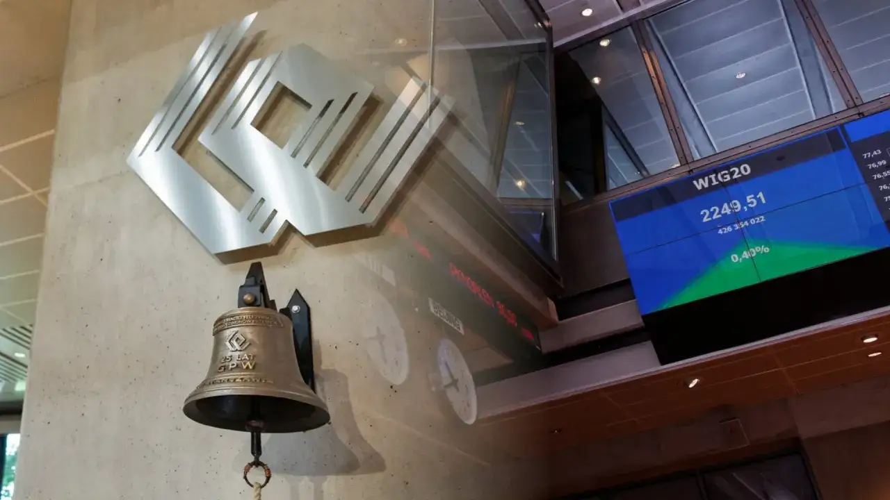 Dzwon giełdowy i logo GPW przypominają o historii, kiedy powstała giełda papier&oacute;w wartościowych w Warszawie. Na ekranie wskaźnik WIG20.