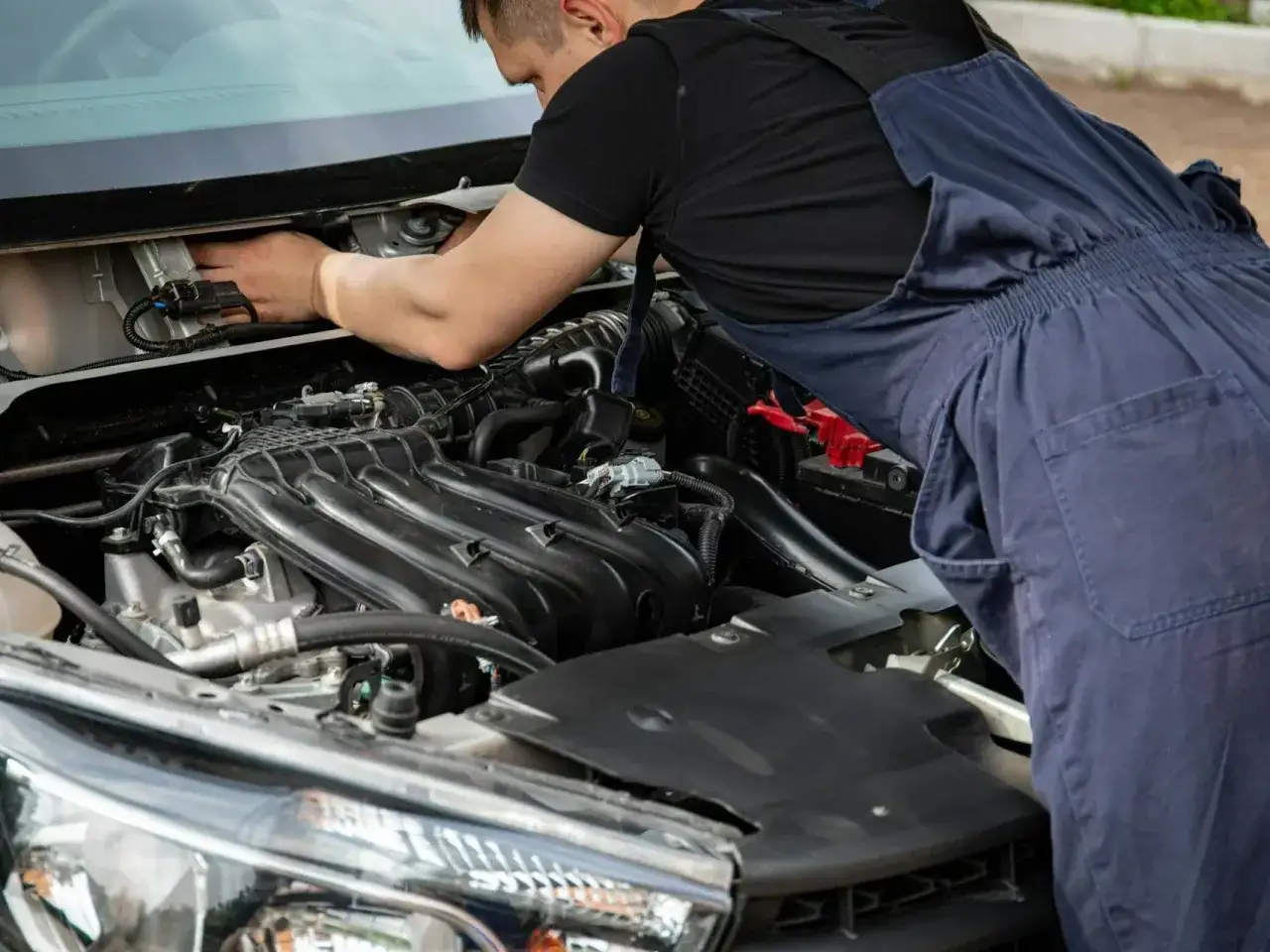 Mechanik samochodowy z kluczem, zamyślony nad uszkodzonym silnikiem