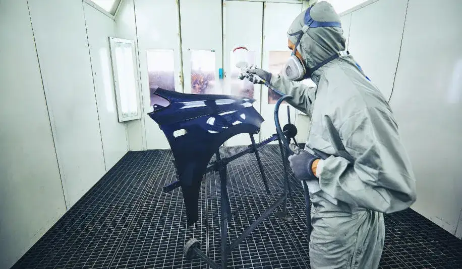 Samochód w komorze lakierniczej, lakiernik przy pracy