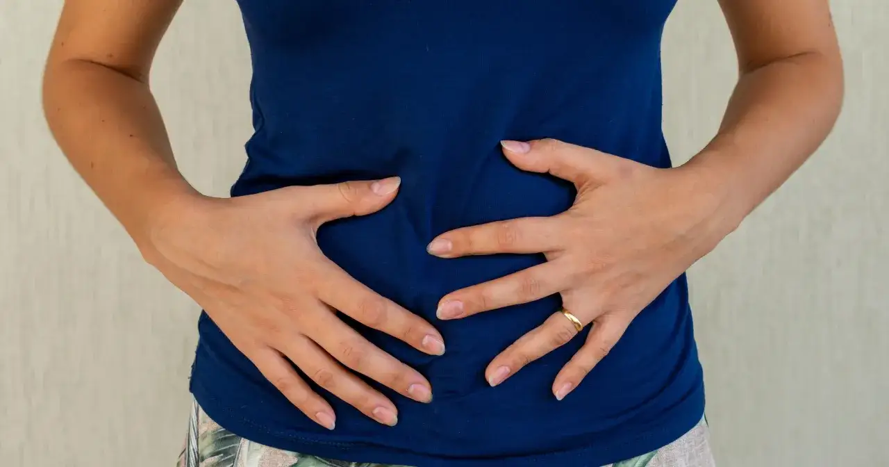 Dłonie obejmują brzuch, gdzie czuć niepokojące przelewanie.