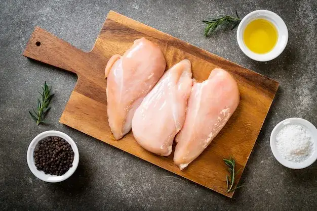 świeża pierś z kurczaka na desce do krojenia