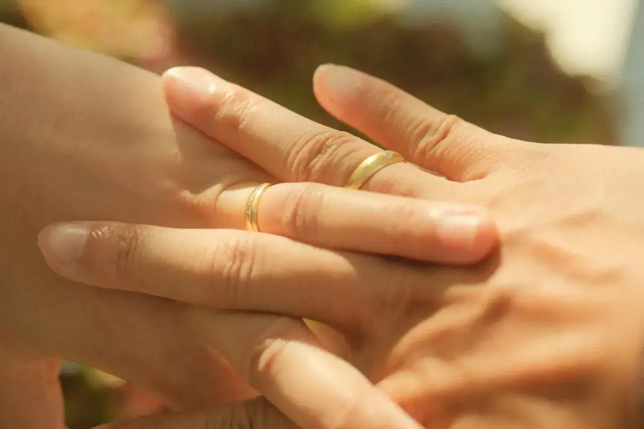 Dłonie z obrączkami, symbol miłości i wsp&oacute;lnej przyszłości. Czas na szczere pytania do partnera.