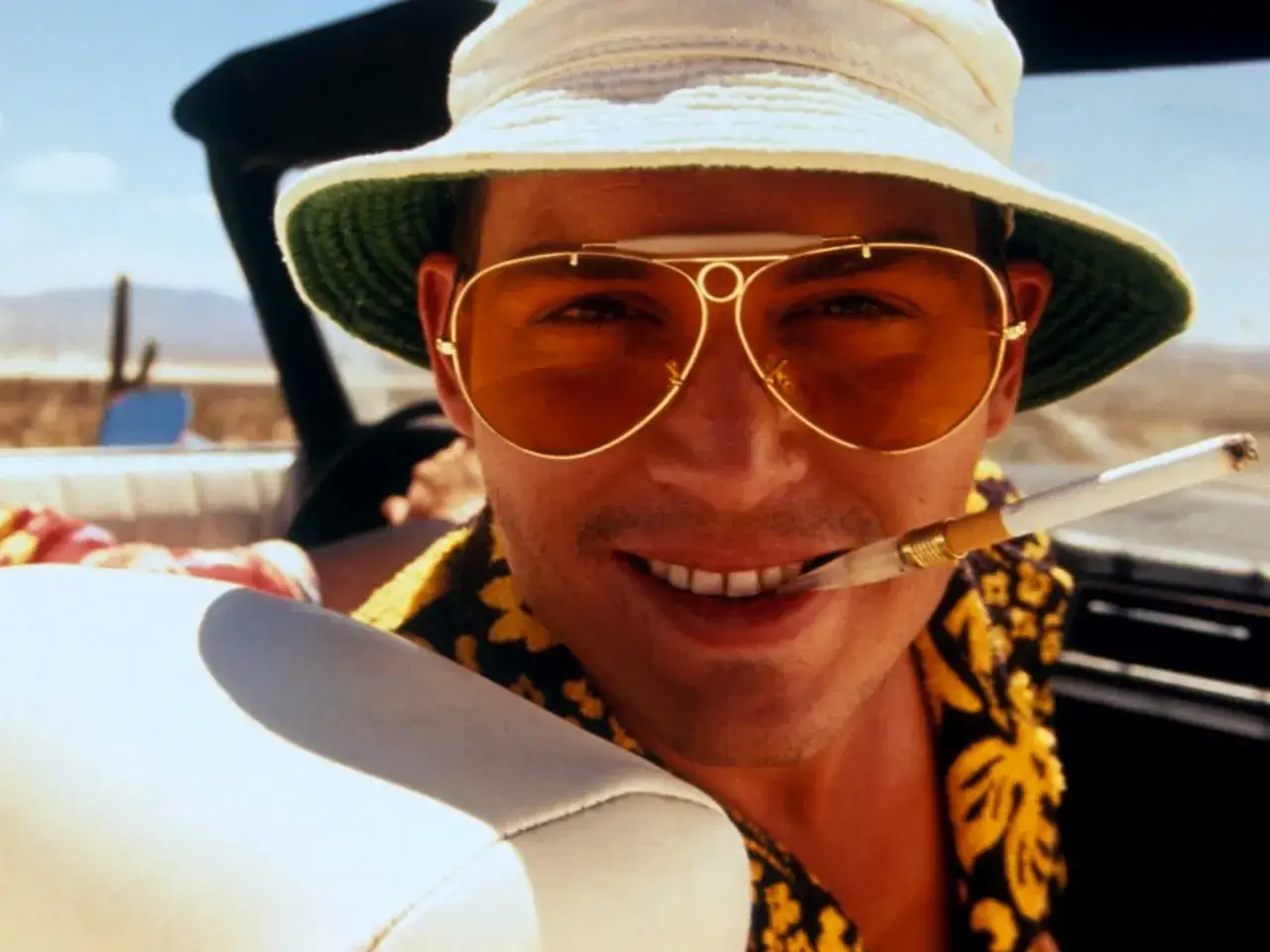 Johnny Depp w okularach i kapeluszu, z papierosem w ustach, w klimacie Las Vegas Parano.