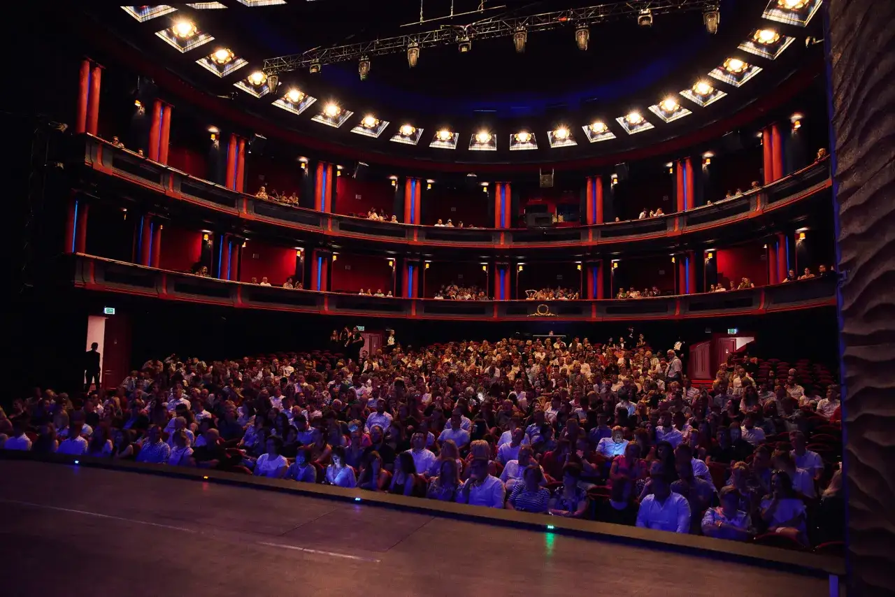 Widownia teatru roma wypełniona po brzegi widzami, czekającymi na rozpoczęcie spektaklu.