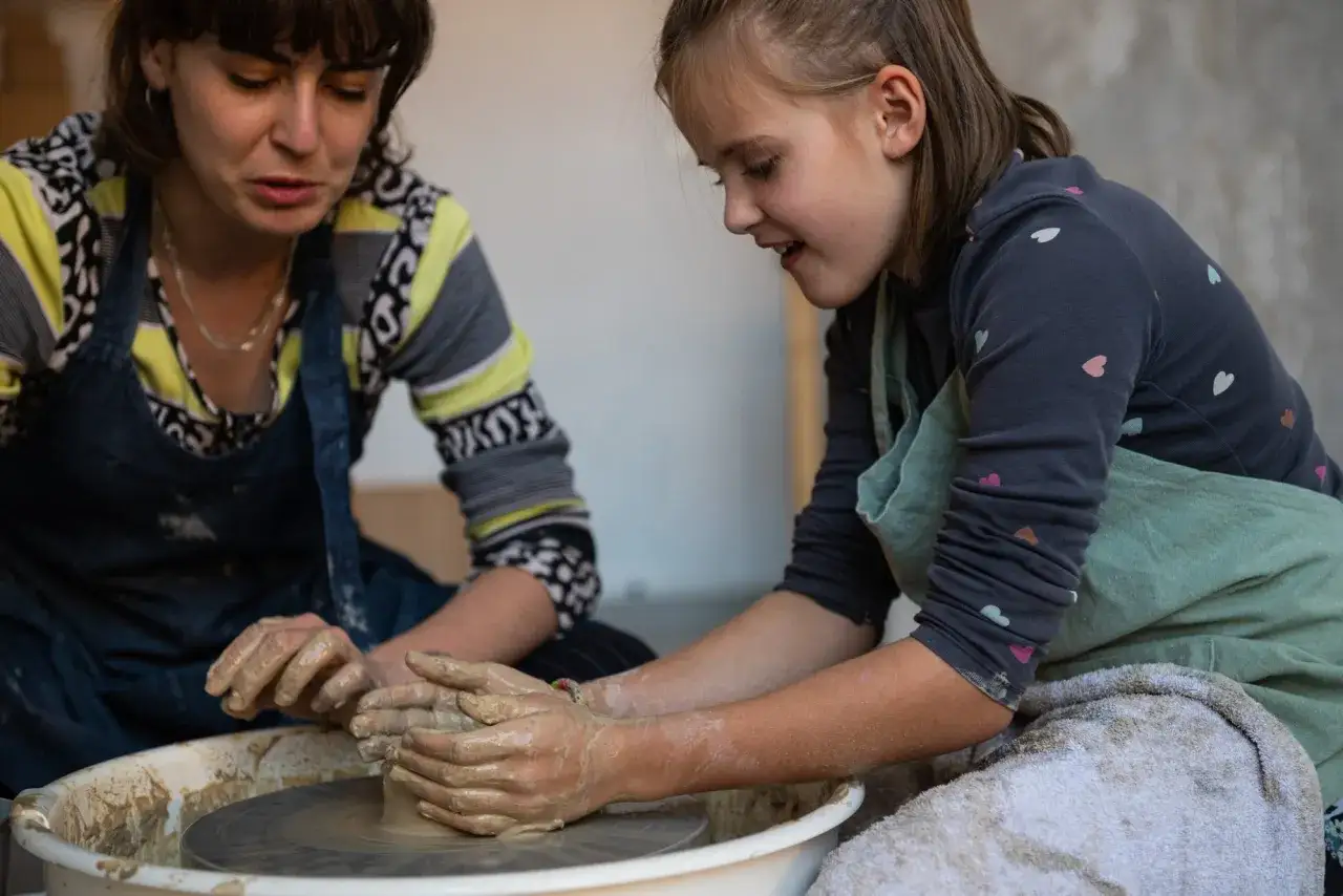 Kobieta lepiąca glinę na kole garncarskim w pracowni ceramicznej