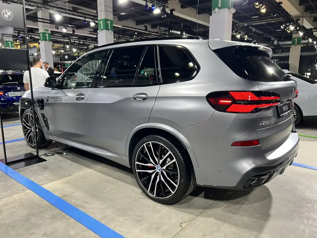 Szare BMW X5 na wystawie. Zbliżenie na tył pojazdu z charakterystycznymi światłami. Warto sprawdzić bmw x5 dane techniczne.
