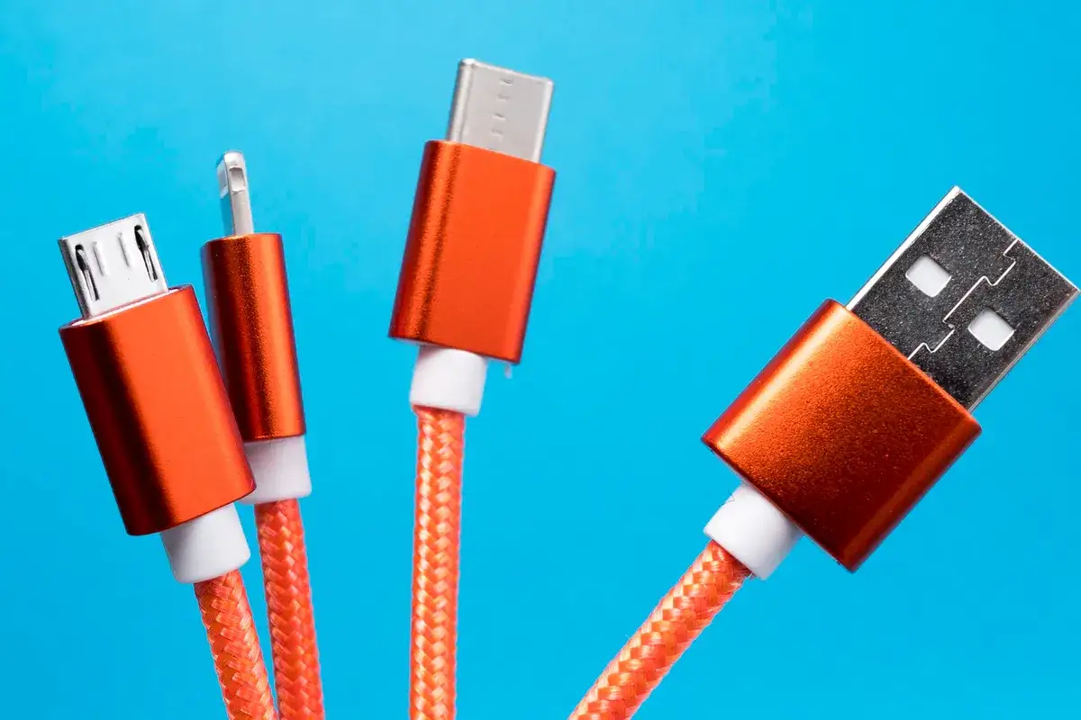 Pomarańczowe kable USB z różnymi końcówkami, gotowe do ładowania urządzeń.
