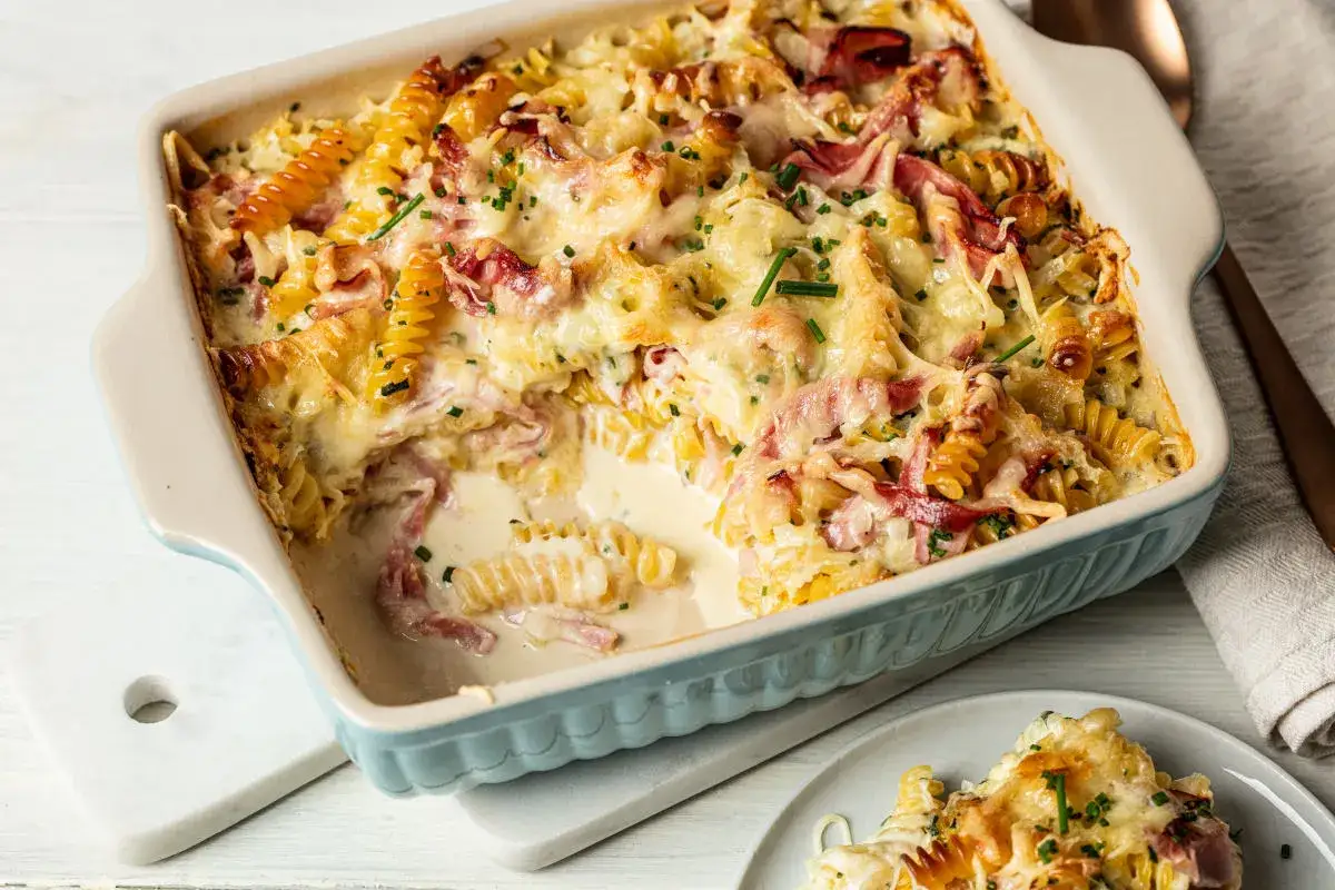 Pyszna zapiekanka makaronowa z szynką, zapieczona pod złotym serem, z dodatkiem świeżego szczypiorku.