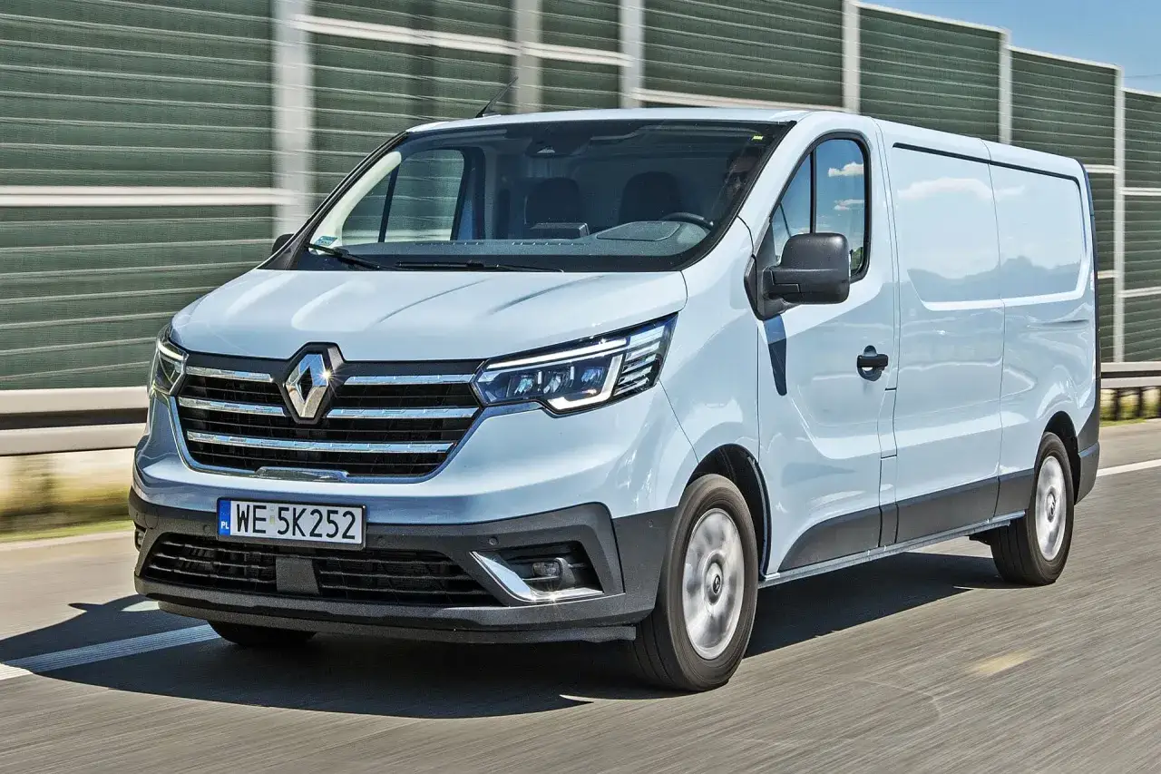 Jasnoszary Renault Trafic 2.0 jedzie autostradą. Pojemność baku tego wszechstronnego vana pozwala na długie trasy.
