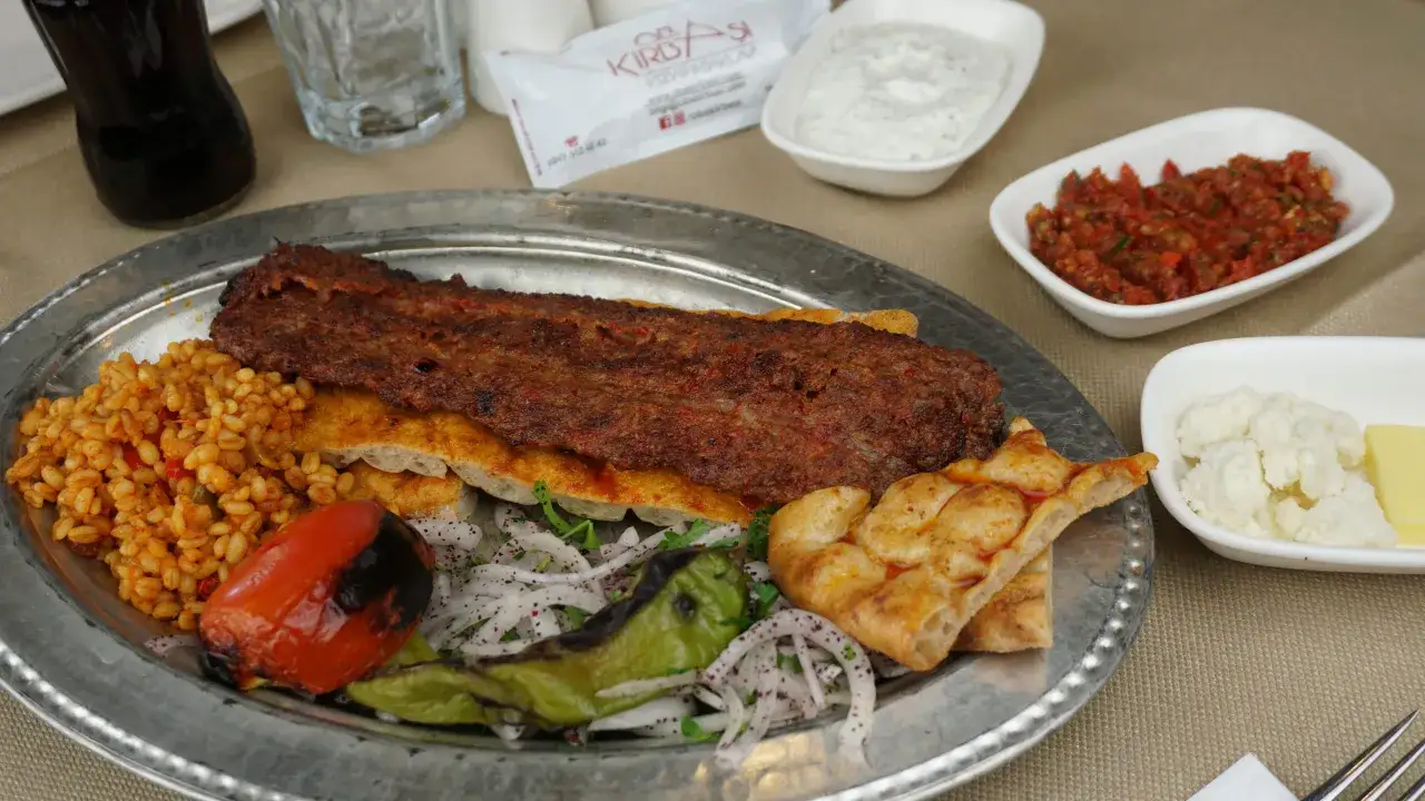 Pyszne tureckie jedzenie: kebab, bulgur, pieczony pomidor i papryka, chleb, sosy.