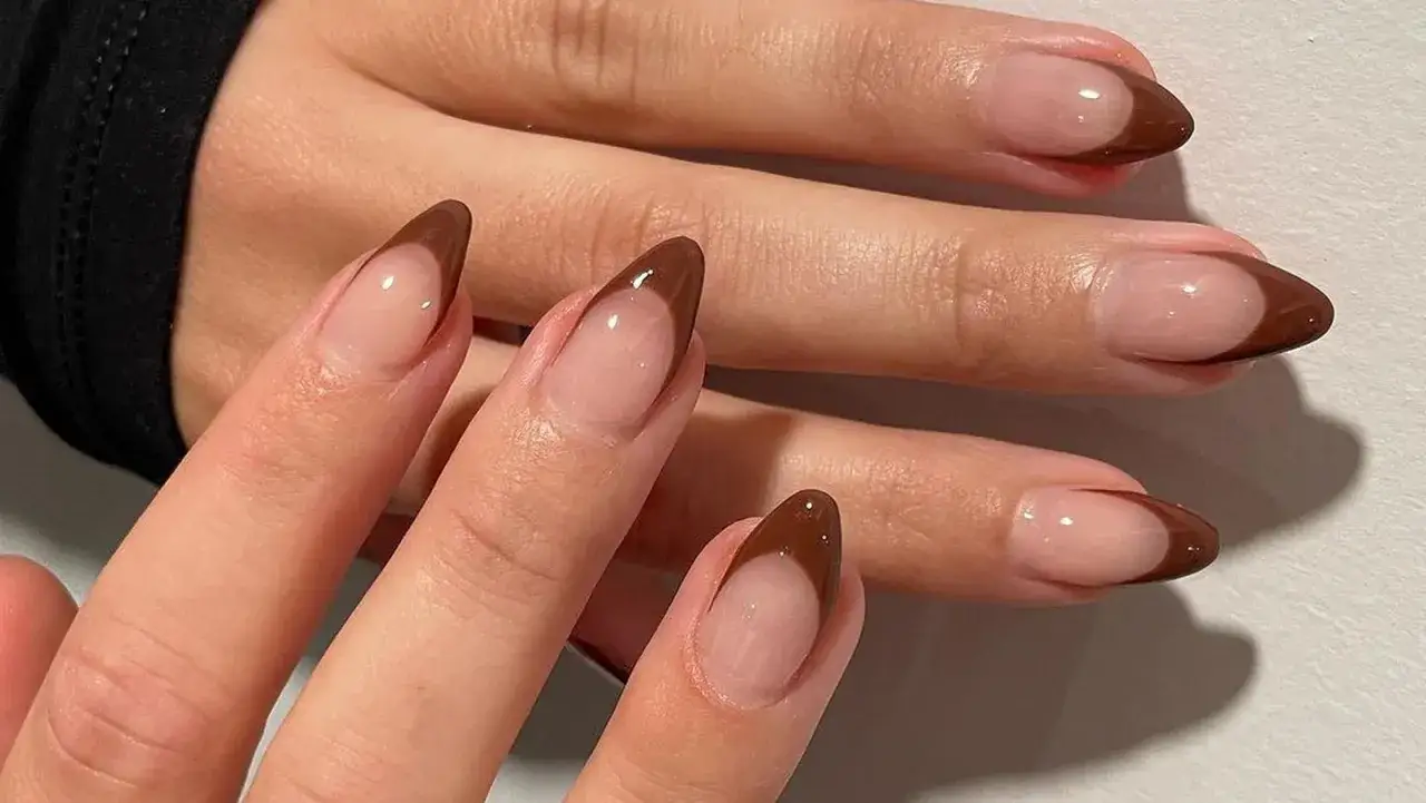 Eleganckie brązowe french paznokcie w kształcie migdałka, podkreślające naturalne piękno dłoni.