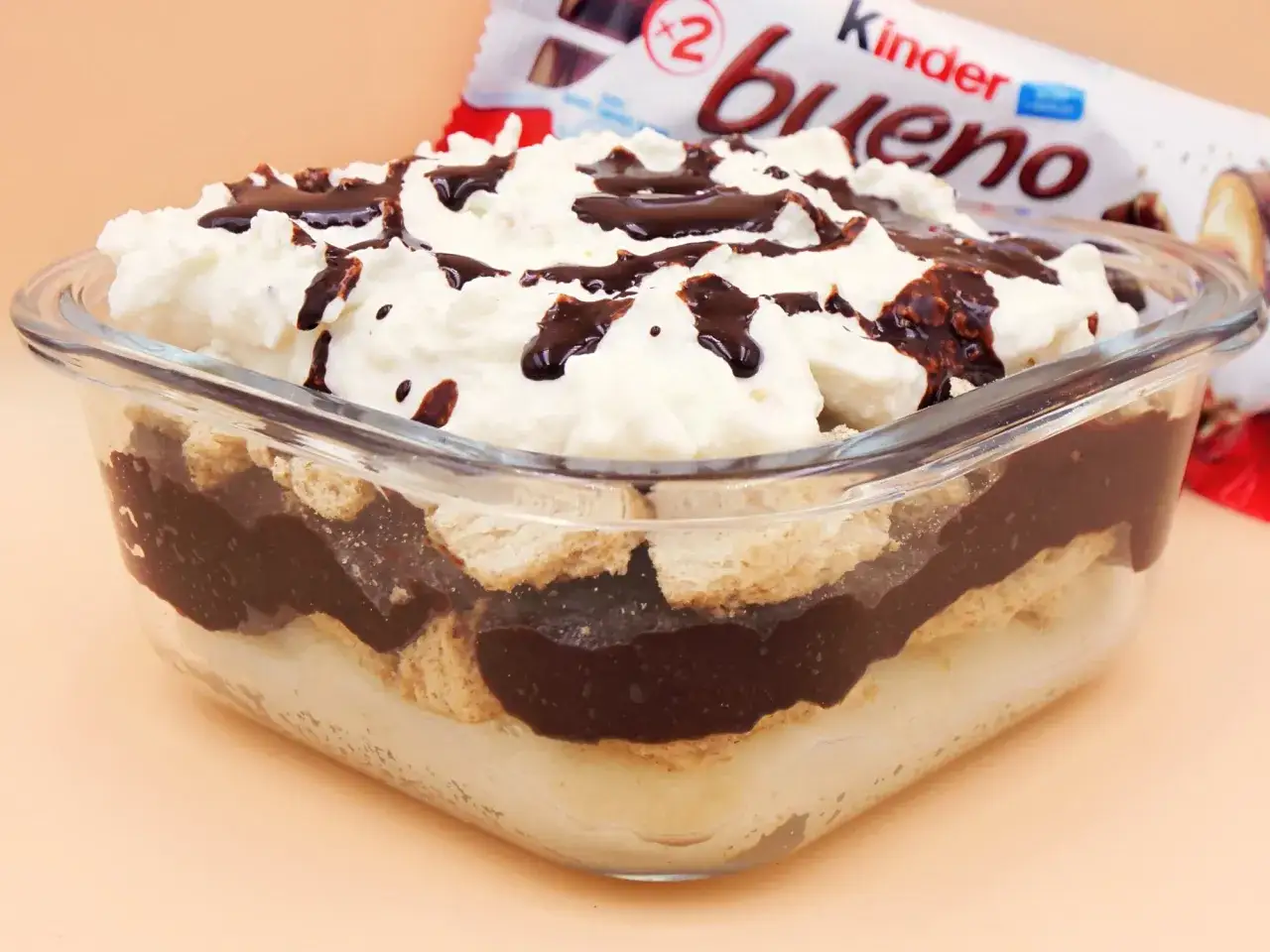 Pyszne ciasto Kinder Bueno w pucharku, przełożone kremem, biszkoptami i czekoladą, polane sosem.