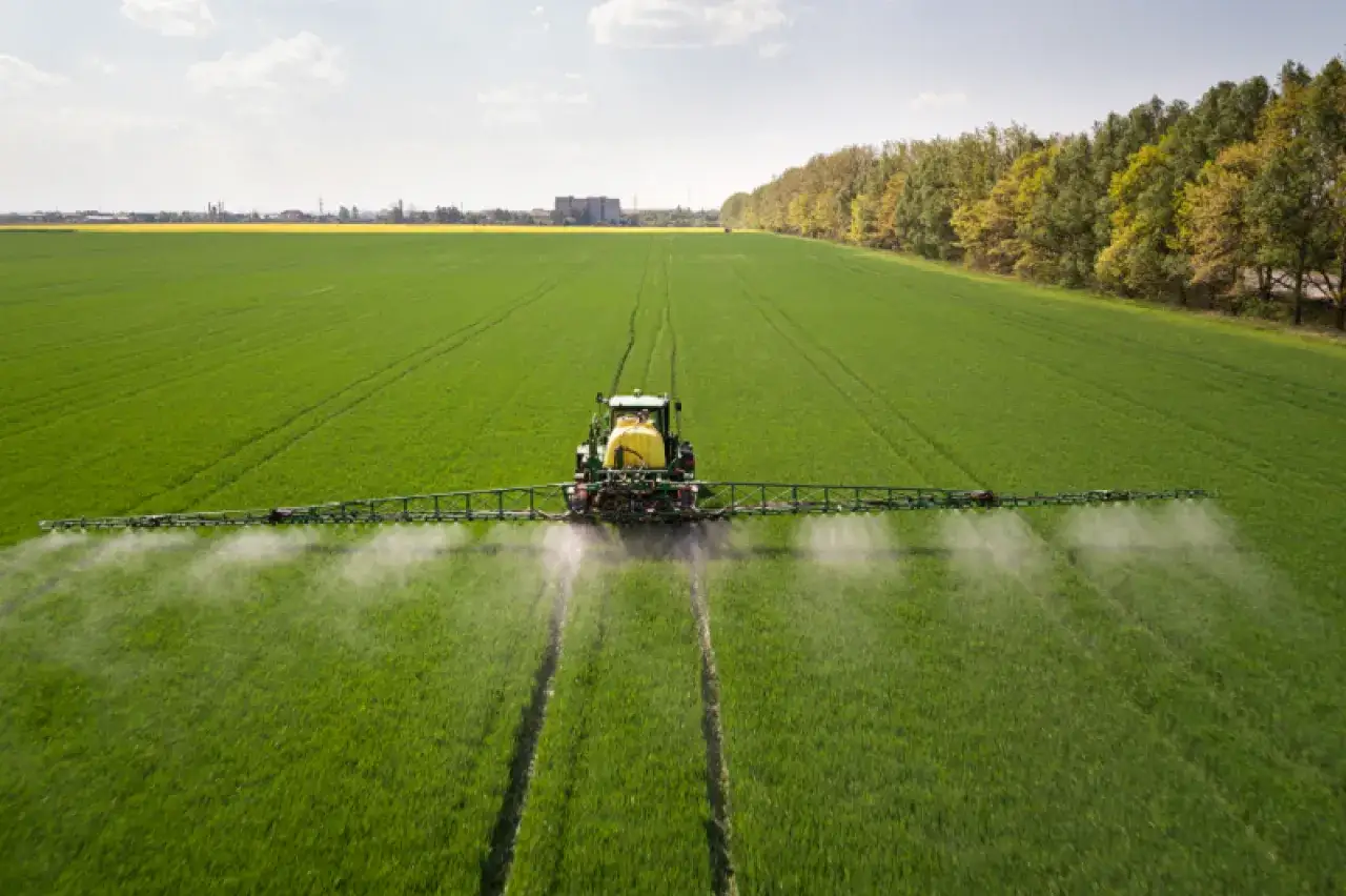 Traktor opryskuje pole, rozprowadzając środek ochrony roślin. Czy to glifosat, co to jest i jak działa?