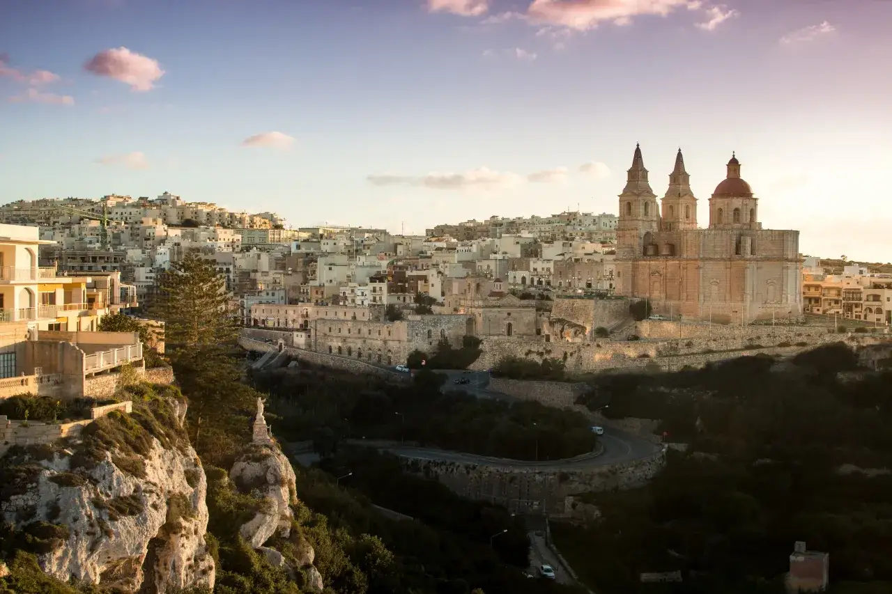 Widok na miasto na Malcie z kościołem i klifem. Ile ludności ma Malta? Około 530 tysięcy mieszkańców.