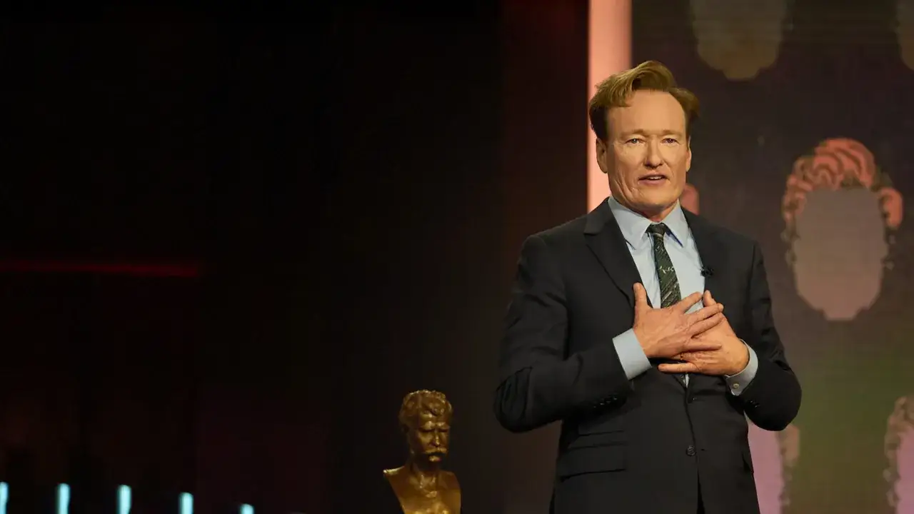 Conan O'Brien, znany amerykański komik stand up, z dłońmi na sercu na scenie.
