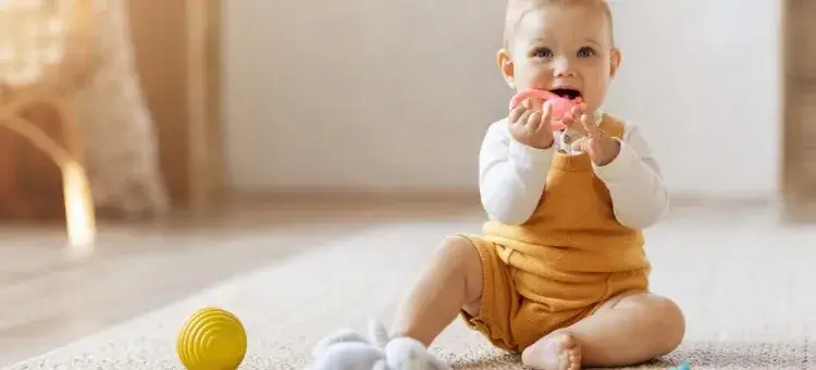 niemowlę siedzące i bawiące się zabawkami