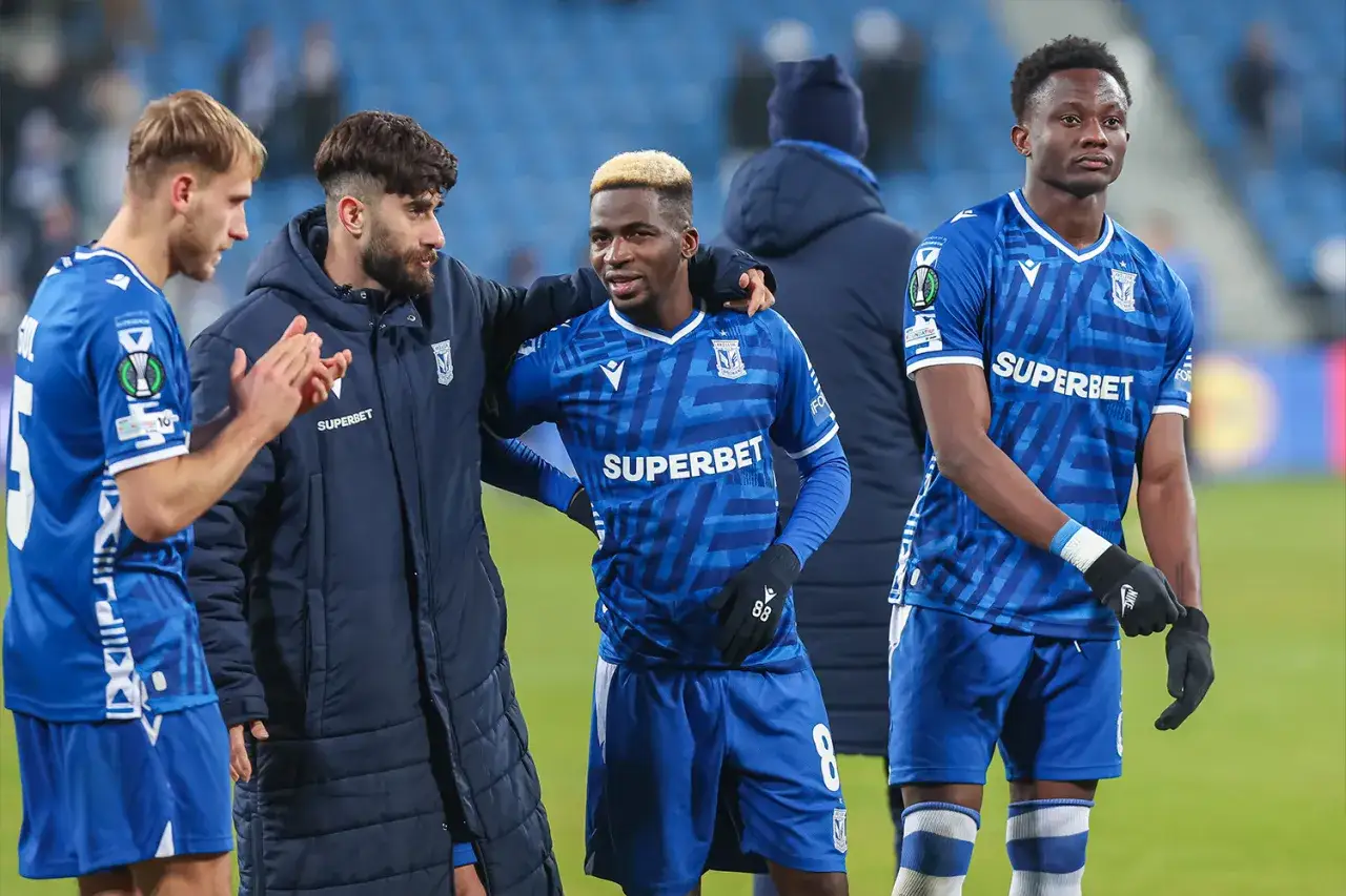 Piłkarze Lecha Poznań w niebieskich strojach, dyskutują o pogłoskach transferowych.