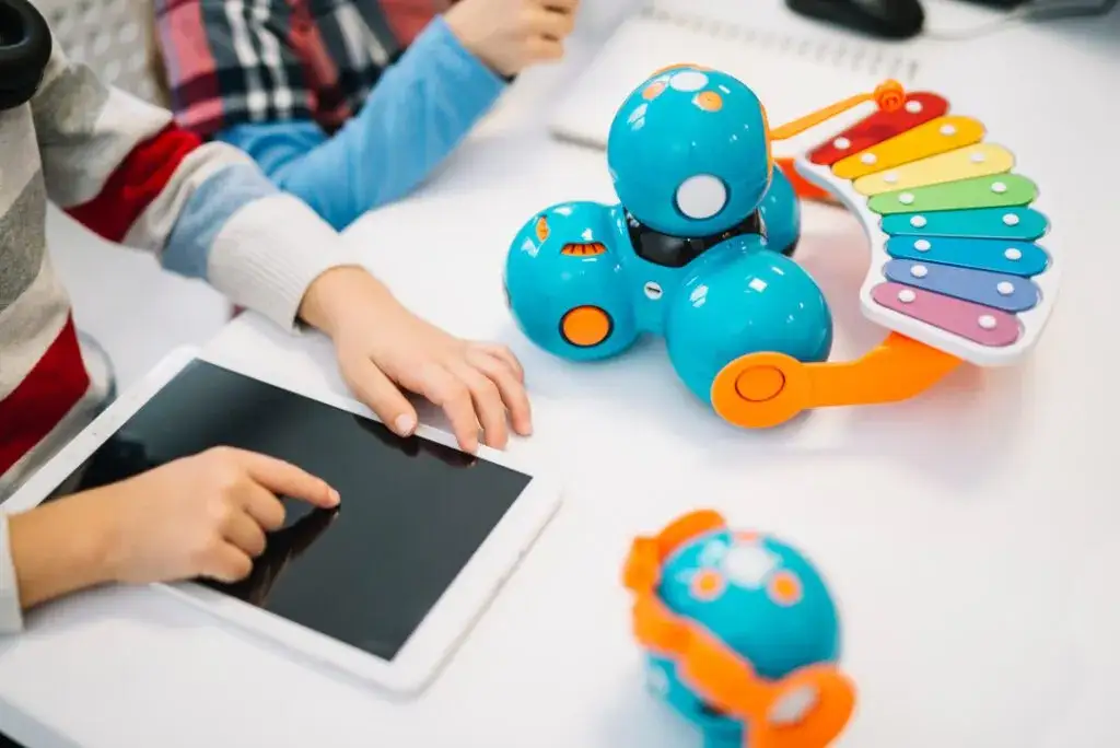 dziecko uczące się programowania na tablecie lub z małym robotem edukacyjnym