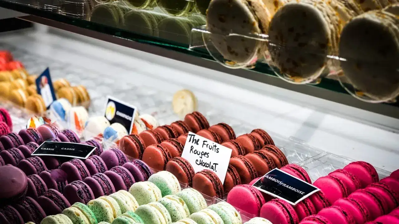 Kolorowe, typowe francuskie słodycze: makaroniki o różnych smakach, od fioletowych po różowe, czekoladowe i owocowe.
