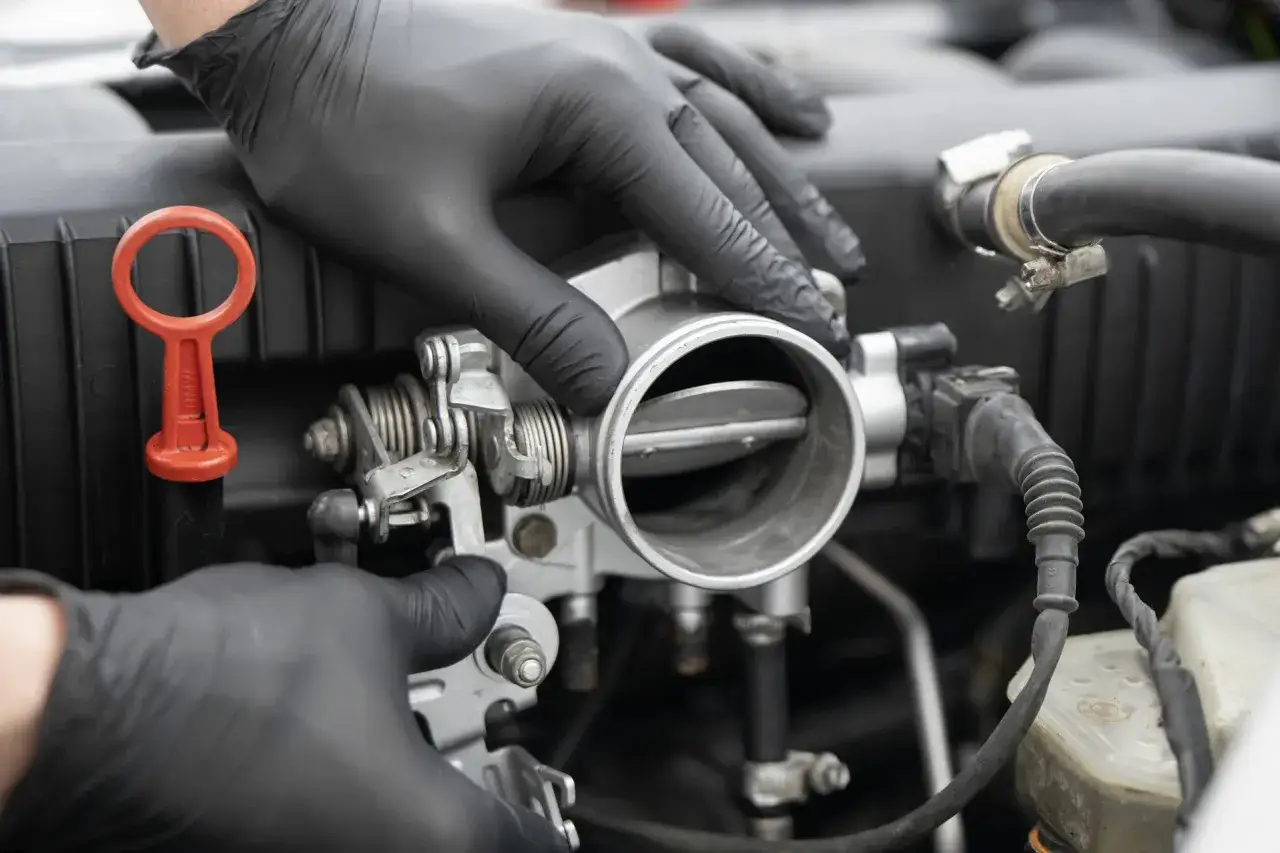 Ręce w czarnych rękawiczkach manipulują przepustnicą, sprawdzając jej działanie.