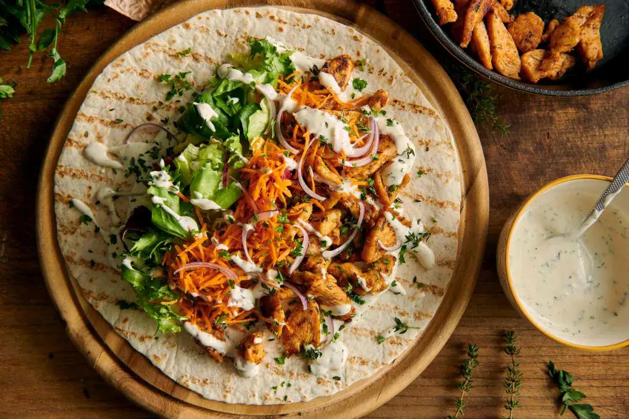 Pyszny kebab na tortilli z kurczakiem, warzywami i kremowymi sosami do kebaba.