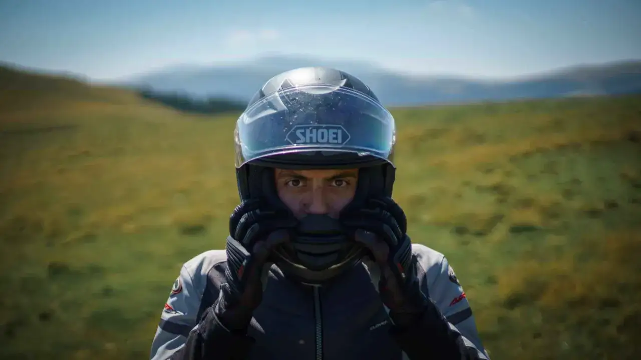 Mężczyzna w kasku motocyklowym Shoei, przygotowuje się do jazdy. Widoczna budowa kasku motocyklowego.