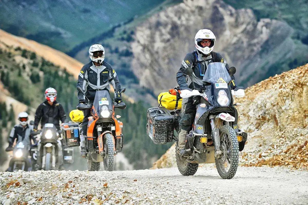 Motocykliści w kaskach i odzieży ochronnej jadący po kamienistej drodze w g&oacute;rach. Jaki przebieg dla motocykla jest duży? Taki, kt&oacute;ry pozwala na takie przygody.
