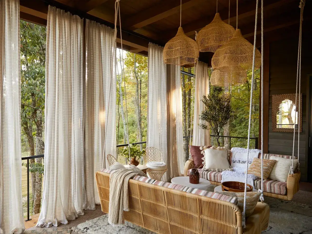 Przytulna weranda z huśtawką i wiklinowymi meblami, gdzie biophilic design łączy się z naturą.