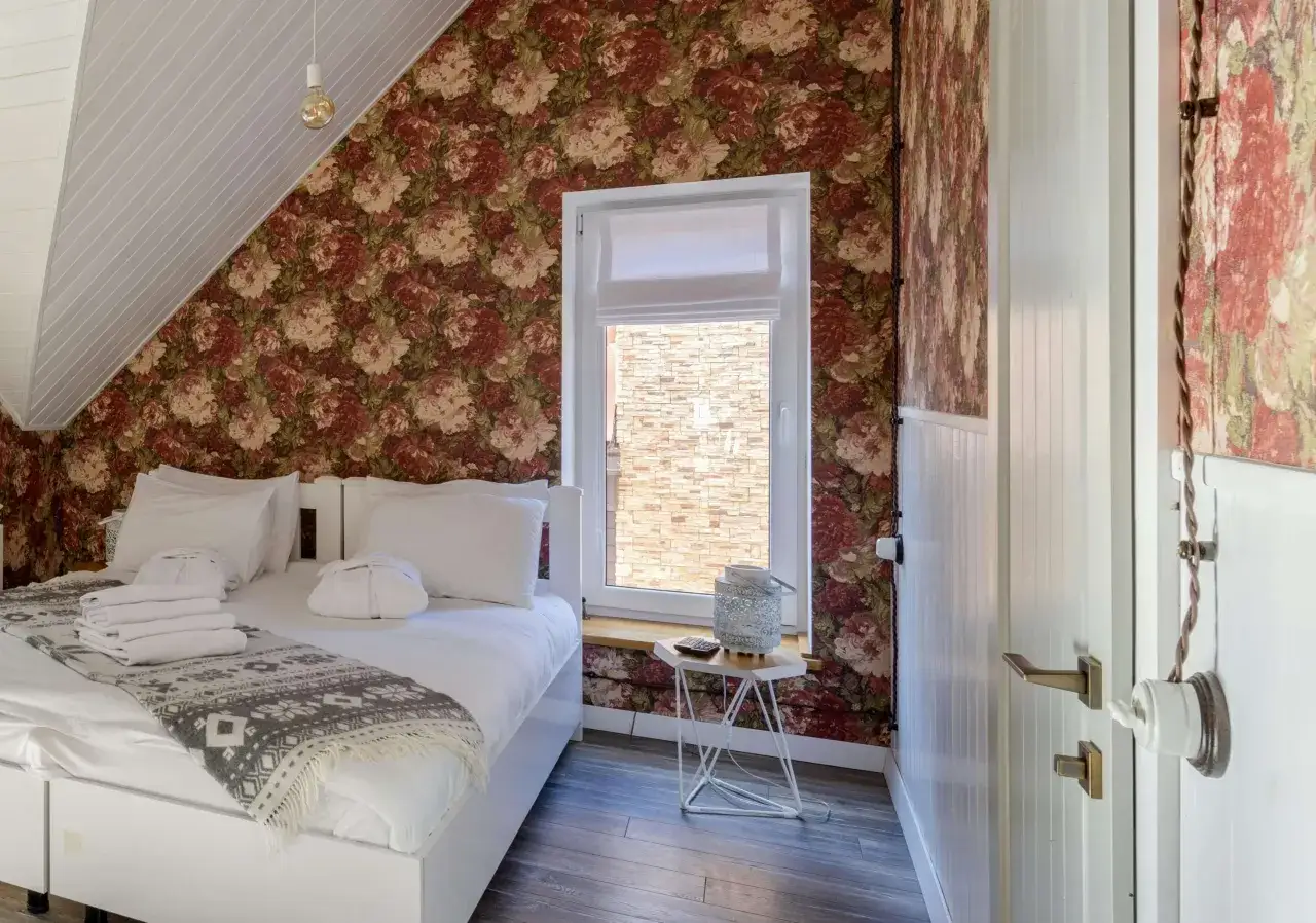 Tapetowanie przy otworach okiennych i drzwiowych dodaje uroku sypialni. Wz&oacute;r kwiatowy pięknie komponuje się z białymi elementami.