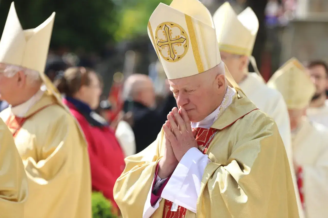 Biskup w złotej szacie z mitrą na głowie, z dłońmi złożonymi do modlitwy, podczas uroczystości. Może to być litania do świętego Stanisława.