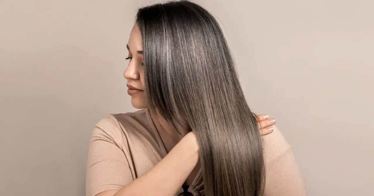 Kobieta z lśniącymi, prostymi włosami po zabiegu laminacji włosów w domu.