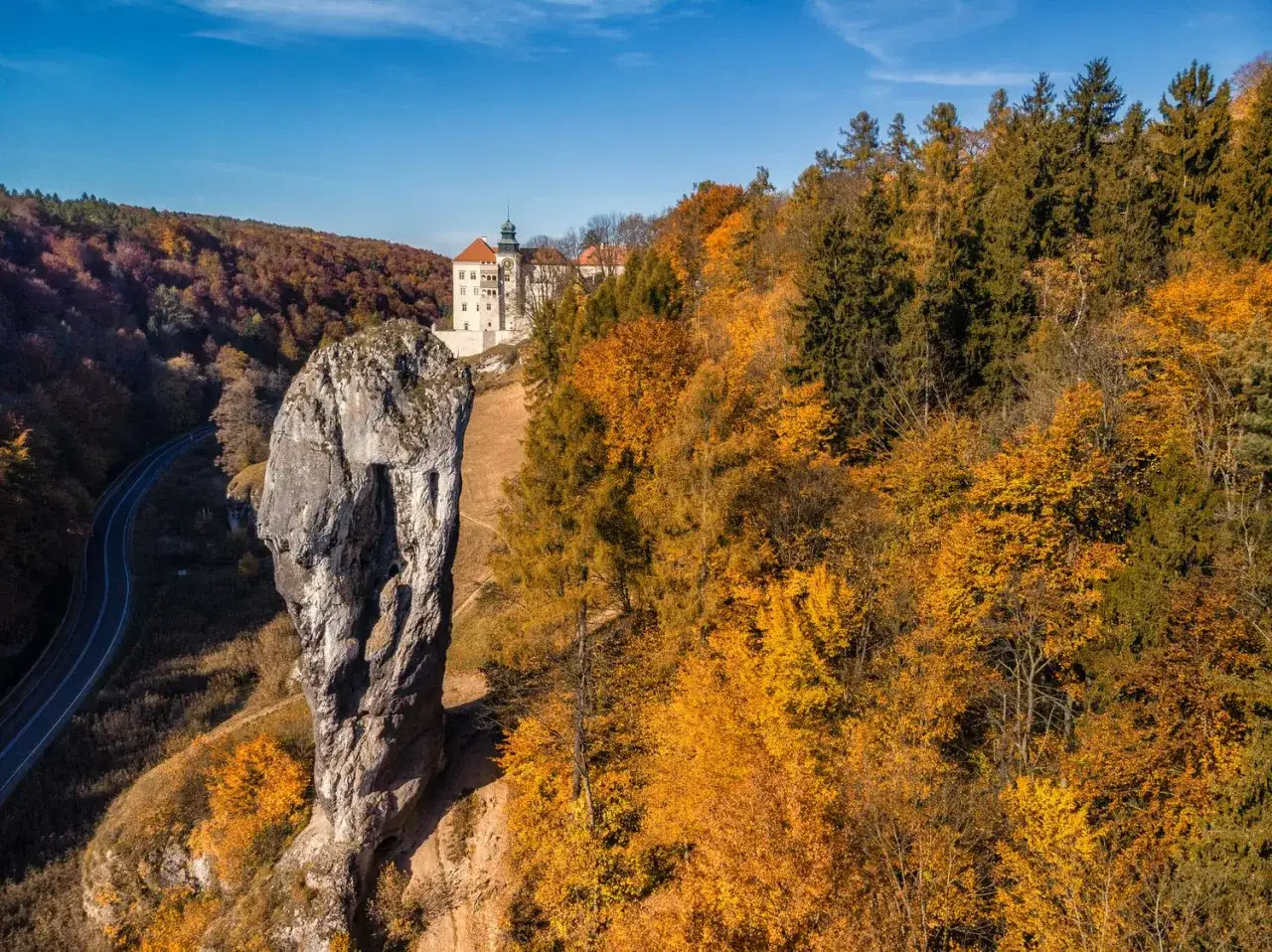 Jesienny krajobraz z zamkiem na wzg&oacute;rzu i skalnym monolicie. Idealne romantyczne miejsca okolice Krakowa na spacer wśr&oacute;d złotych liści.