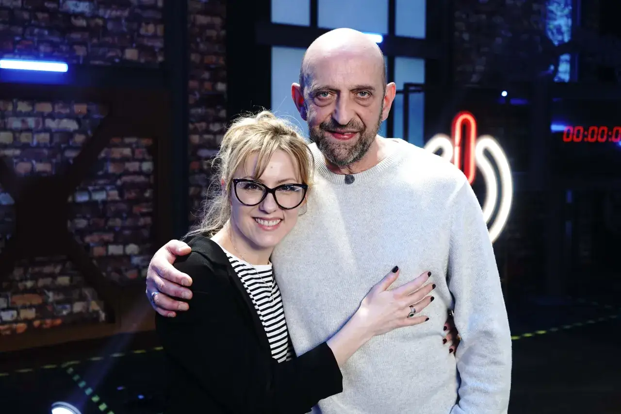 Para uczestników, tworząca power couple, uśmiecha się do kamery. Kobieta obejmuje mężczyznę, który odwzajemnia gest.