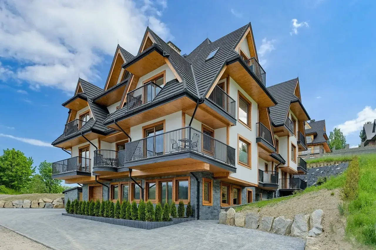 Nowoczesne apartamenty Bachledzki Wierch z drewnianymi elementami i balkonami, otoczone zielenią.