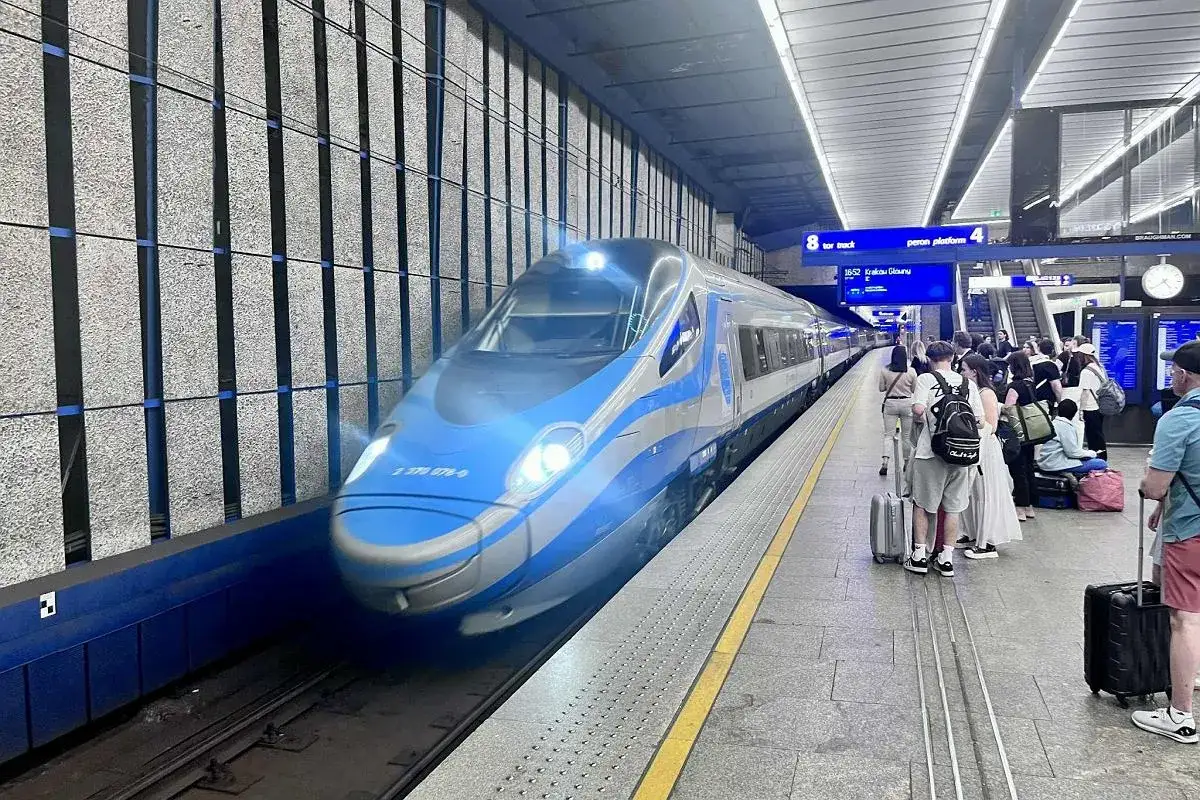 Błękitno-biały pociąg Pendolino na peronie, gotowy do podróży z Warszawy do Zakopanego. Pasażerowie z bagażami czekają na odjazd.
