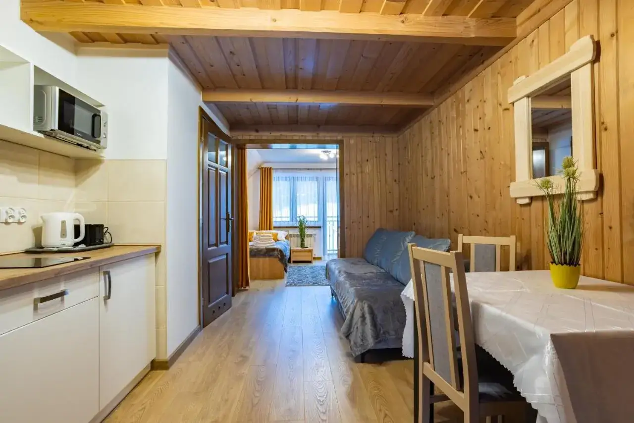 Przytulne wnętrze z aneksem kuchennym, kanapą i stołem. W tle sypialnia. Idealne miejsce na wypoczynek, niczym szarotka bukowina tatrzańska.