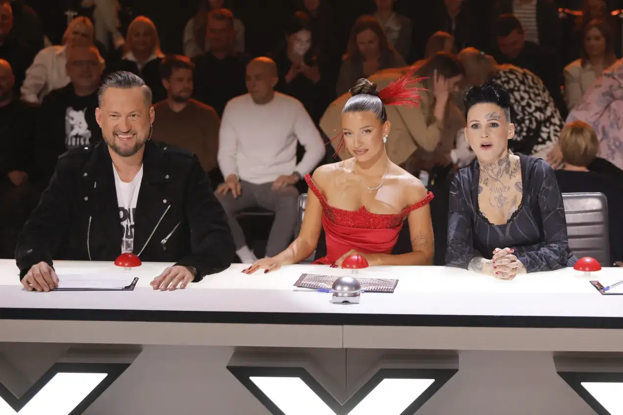 Jurorzy Mam Talent 2026 oceniają uczestnik&oacute;w. Na pierwszym planie siedzą: mężczyzna w czarnej ramonesce, kobieta w czerwonej sukni z pi&oacute;rami i kobieta z tatuażami.