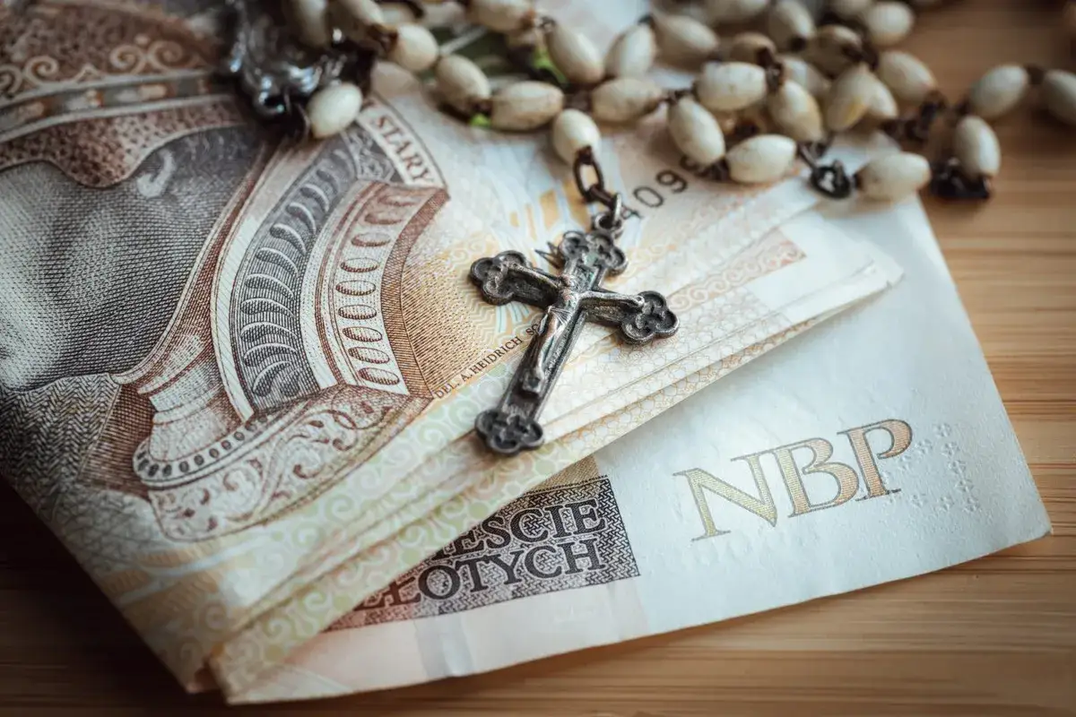 Kiedy ksiądz idzie na emeryturę, jego r&oacute;żaniec spoczywa na banknotach.