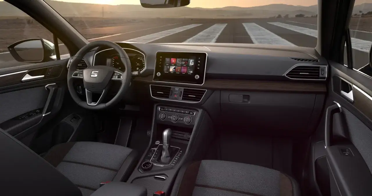 Wnętrze Seat Tarraco z ekranem dotykowym, kierownicą i wygodnymi siedzeniami. Widok z perspektywy kierowcy na drogę.