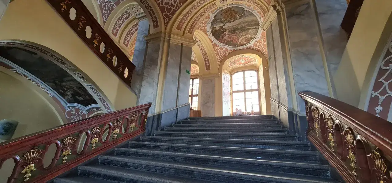Schody w muzeum mieszczaństwa Wrocław, ozdobione malowidłami na suficie i bogatymi zdobieniami.