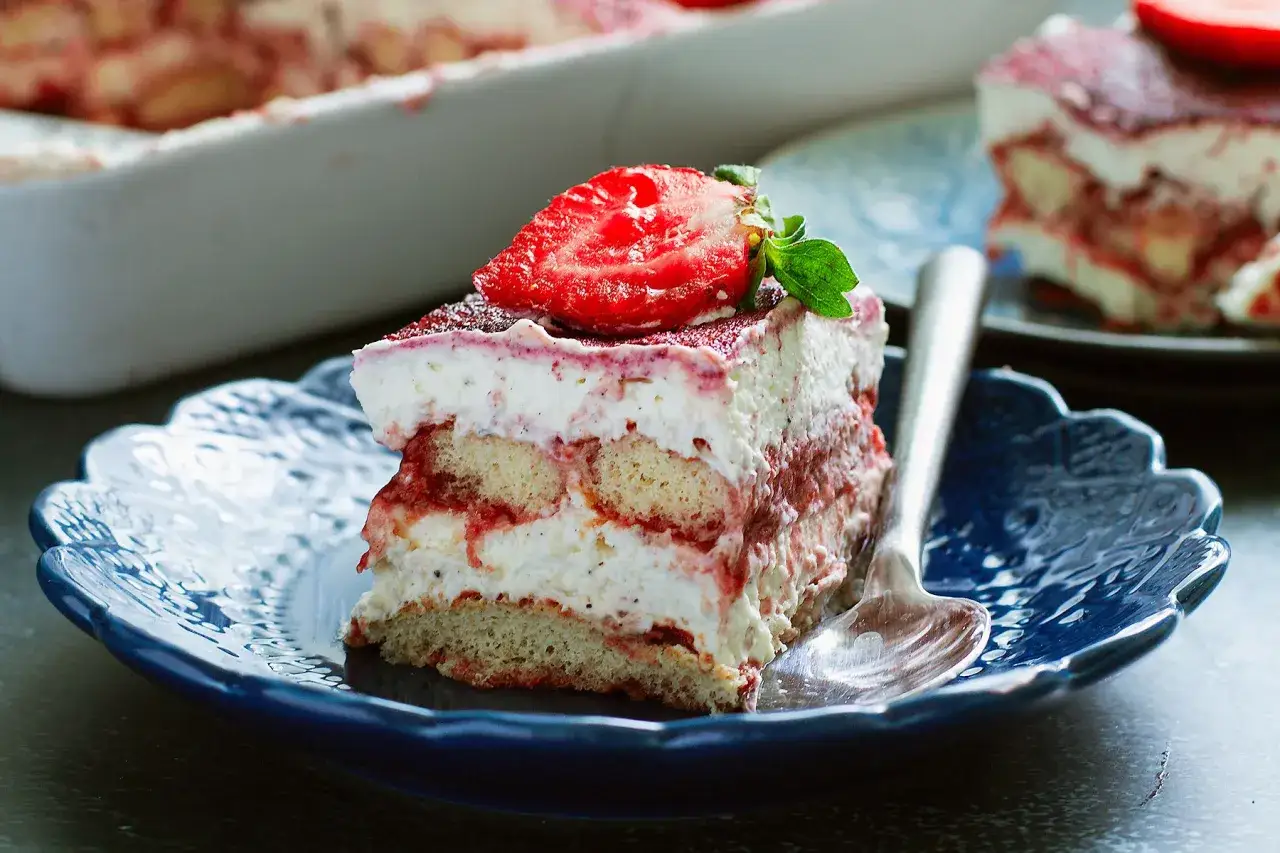 Pyszne tiramisu truskawkowe z bitą śmietaną i biszkoptami, ozdobione świeżą truskawką. Klasyczne tiramisu kontra wersja owocowa.