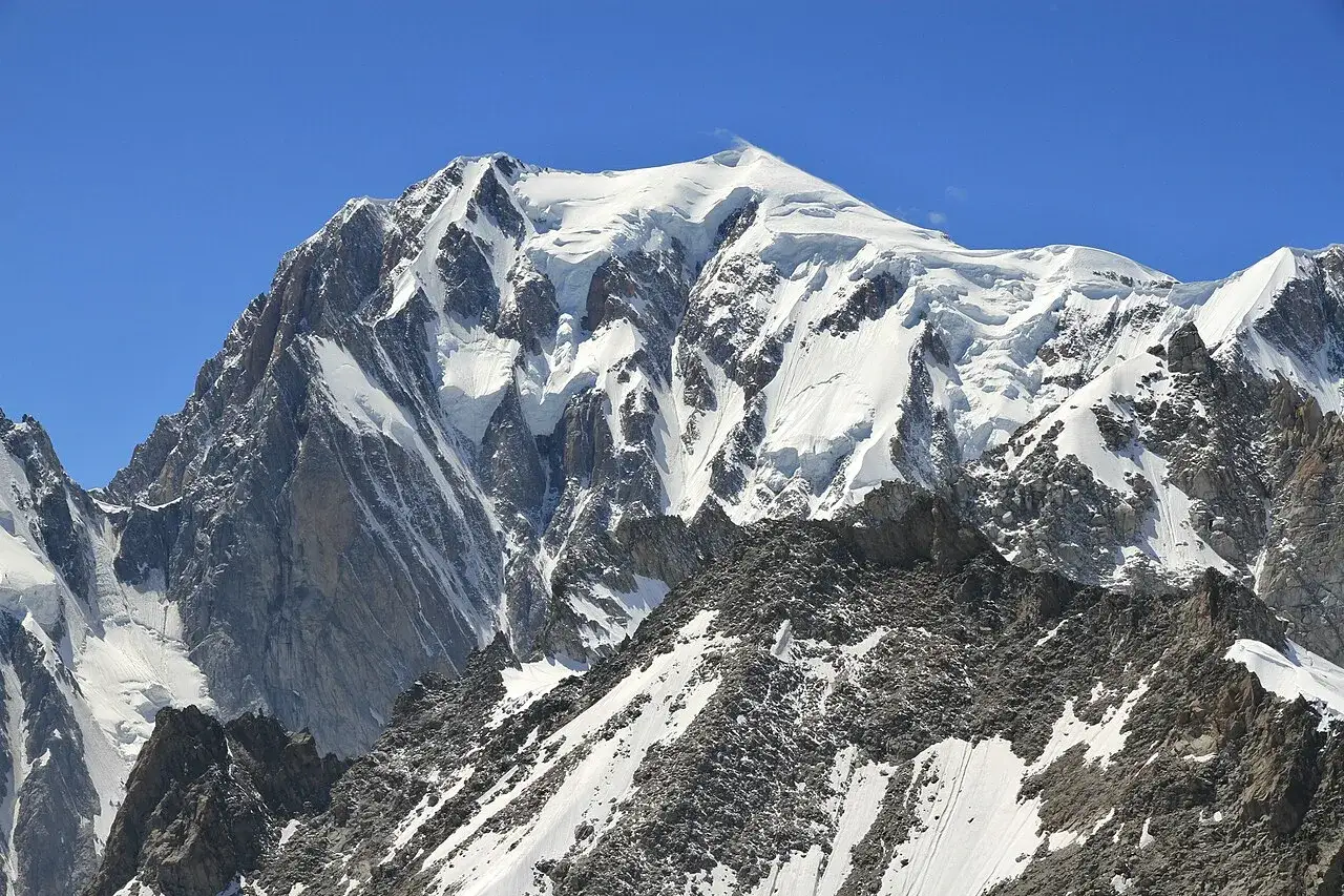 Majestatyczny, ośnieżony najwyższy szczyt Alp, Mont Blanc, lśni w słońcu na tle błękitnego nieba.