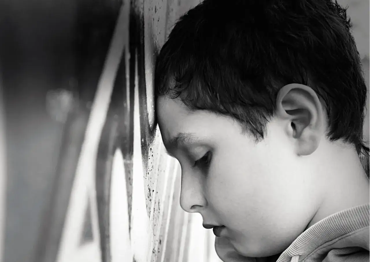 Smutny chłopiec opiera głowę o ścianę. Jak wspierać dziecko z depresją? Potrzebuje Twojej uwagi i zrozumienia.
