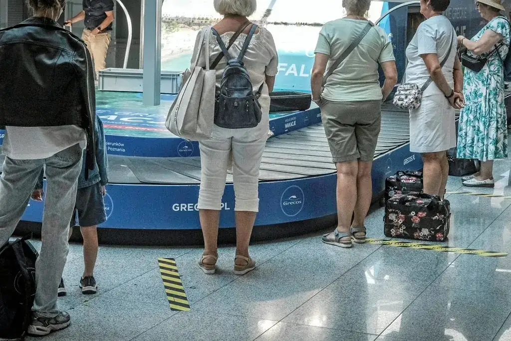 pasażerowie na lotnisku odbierający bagaż