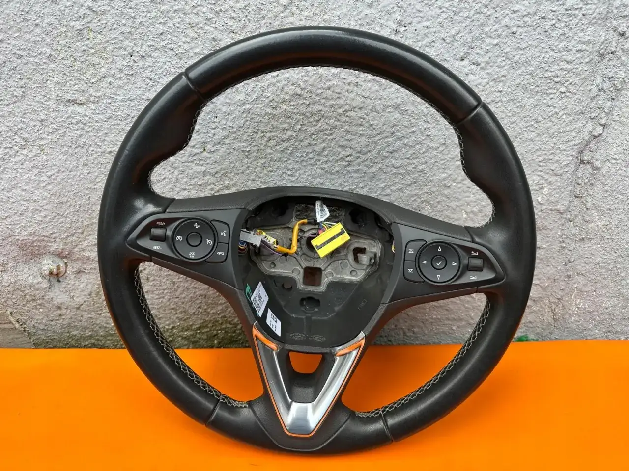 Kierownica Opel Astra J z przyciskami sterowania radiem i tempomatem. Skórzana, z ozdobnym elementem.