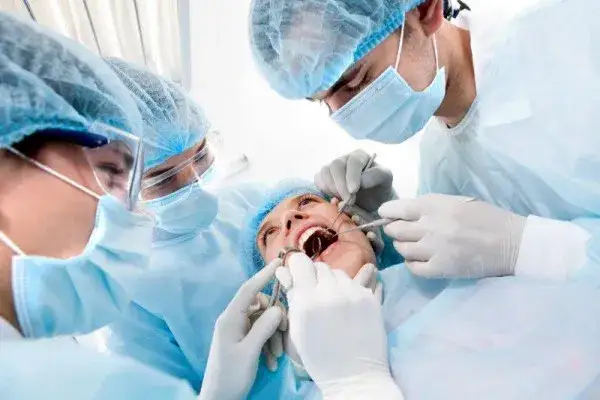 dentysta i asystentka w maskach i przyłbicach podczas zabiegu