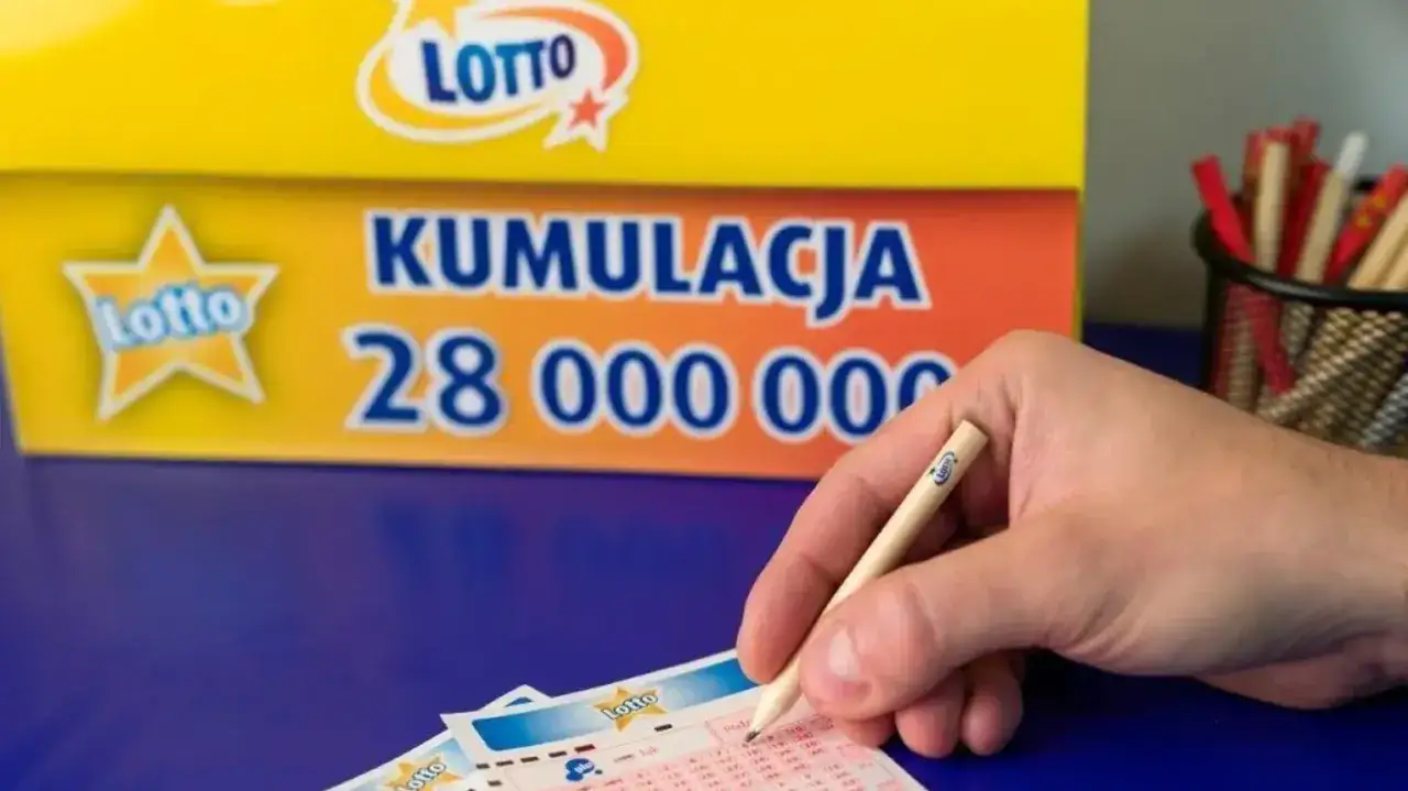 Ręka z ołówkiem zaznacza liczby na kuponie Lotto. Tło informuje o kumulacji 28 milionów złotych, co oznacza lotto z plusem.